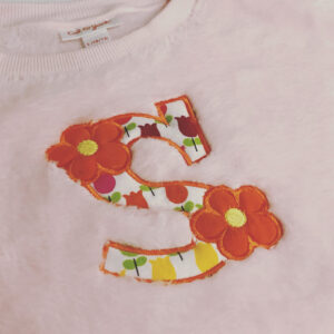 Whimsical single lowercase letter with flowers appliqué
